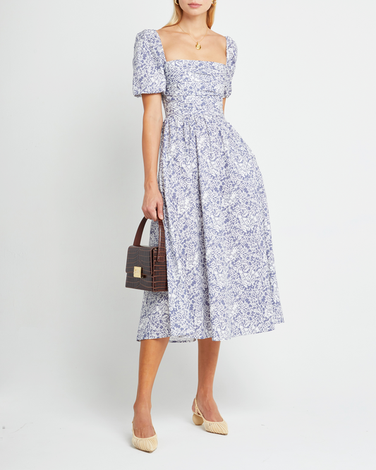 First image of River Dress, a purple midi dress, square neckline, short puff sleeves, gathered bodice, floral print