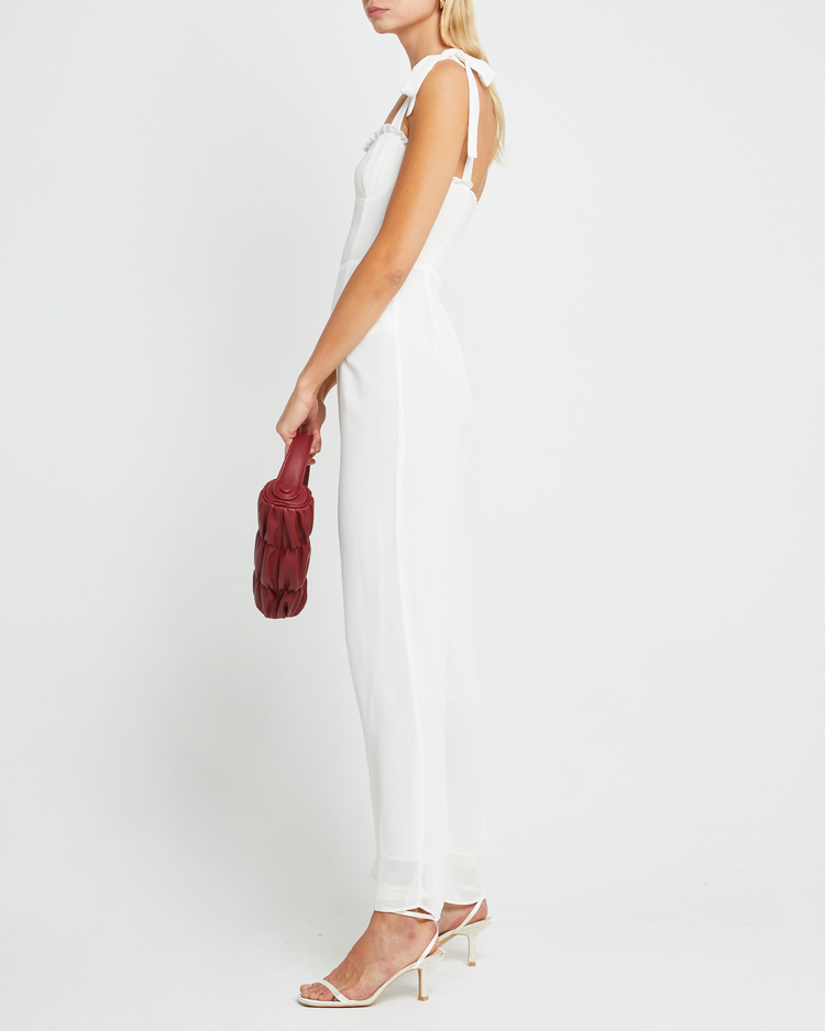 Fifth image of Blair Jumpsuit, a white jumpsuit with straight-leg lined pants, adjustable tie straps, cup detail, neckline ruffles, and a back zipper