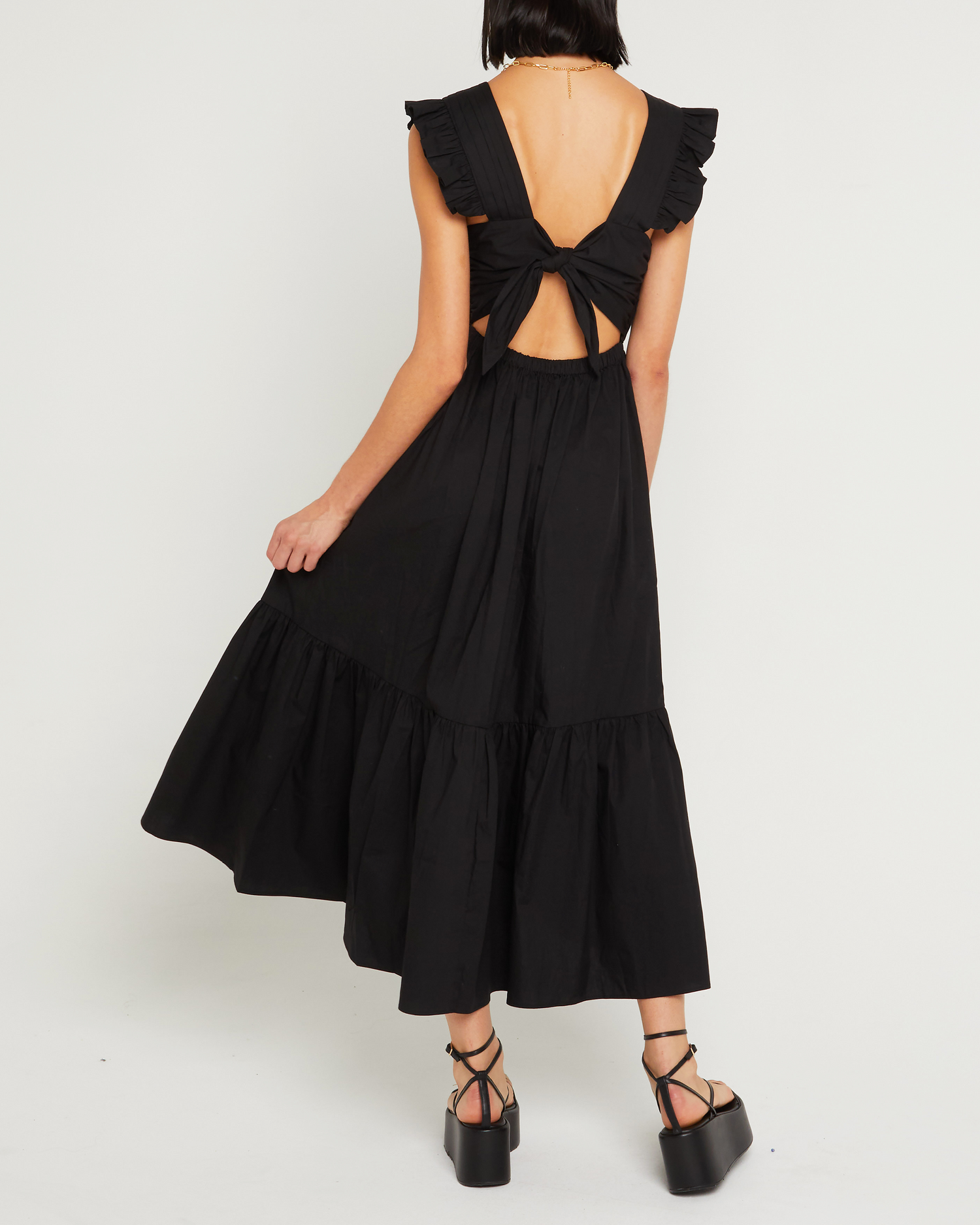 Fifth image of Stella Dress, a black midi dress, front buttons, ruffle sleeve, open back, tied ribbon, bow, tiered