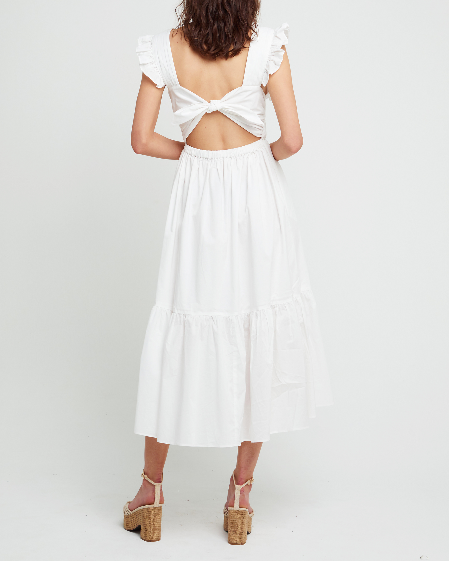 Second image of Stella Dress, a white midi dress, front buttons, ruffle sleeve, open back, tiered, tie, ribbon, bow