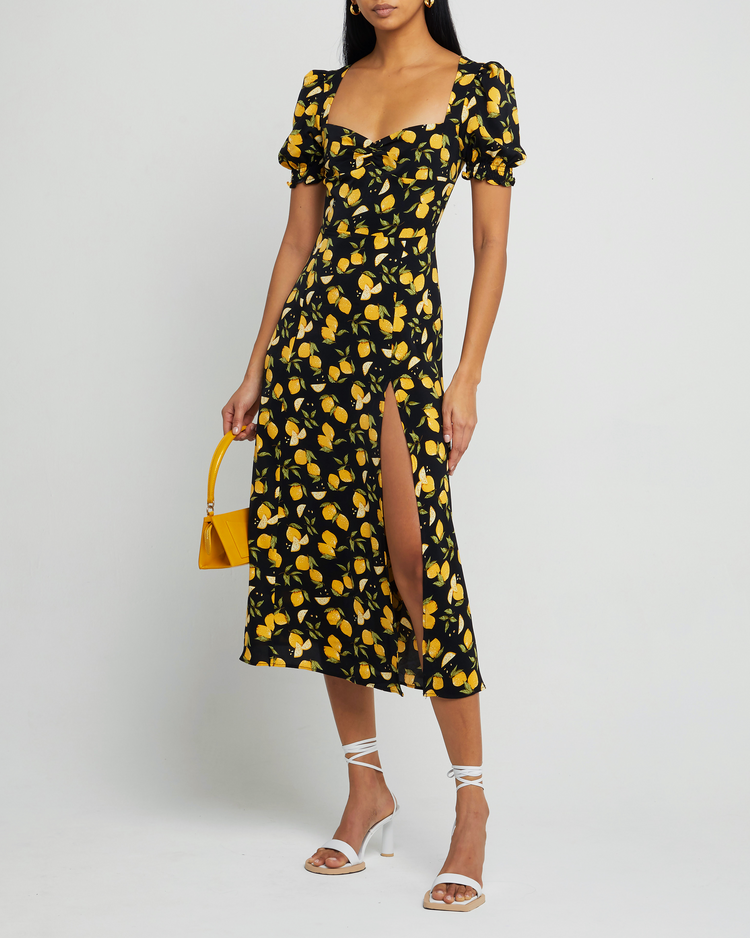 First image of Melanie Dress, a black midi dress, side skirt slit, yellow lemon print, short sleeves, puff sleeves, cap sleeves, sweetheart neckline